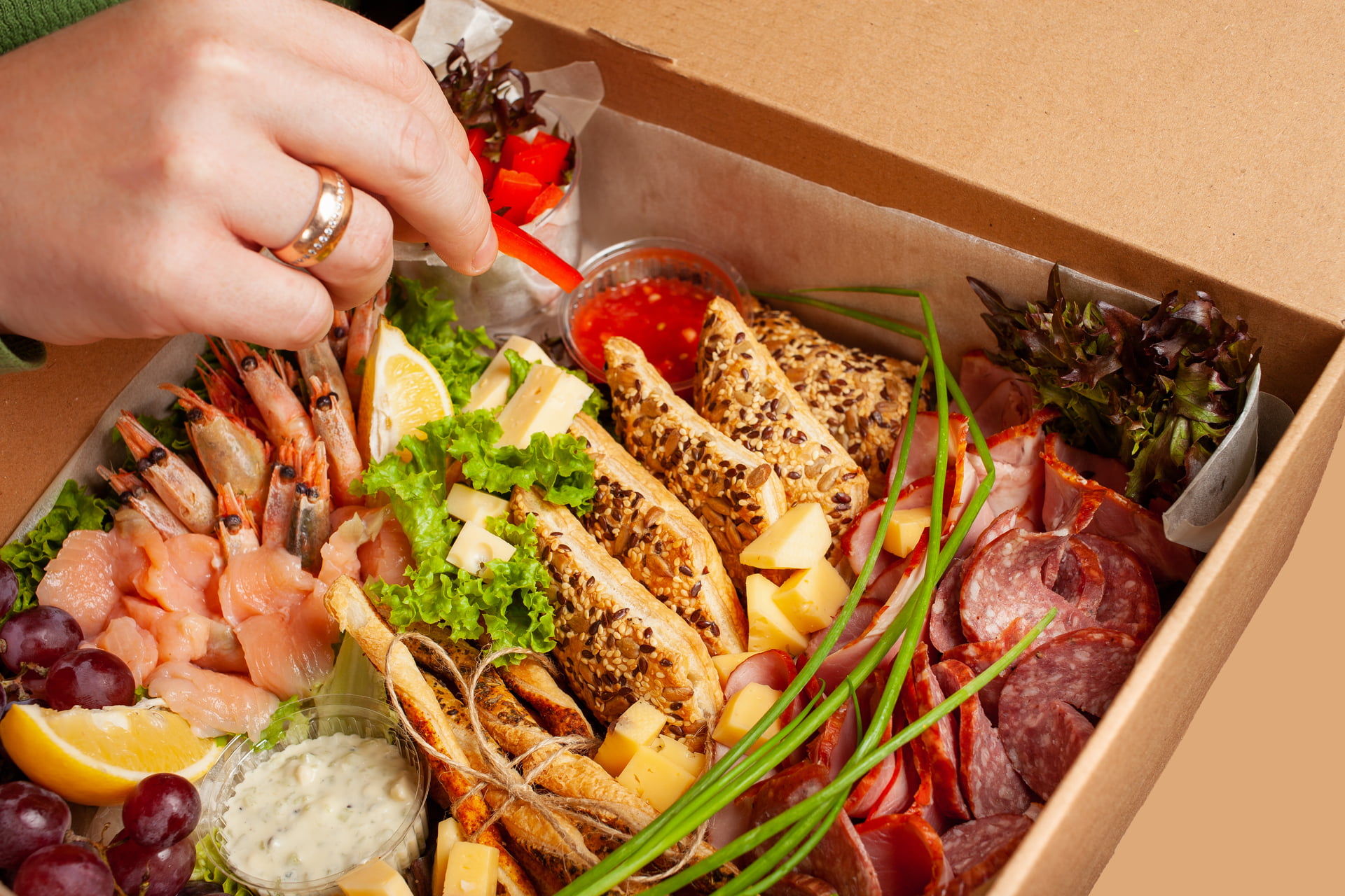 A box of food, cheese, breads, fish, shrimp. Food delivery for the company, romantic, office dinner at home. Beautiful composition of food in a box, convenient carrying, fresh products.